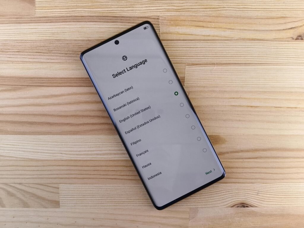 Close-up of smartphone with language selection screen on wooden table.