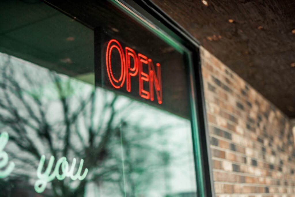 A red neon 'Open' sign glows brightly on a brick storefront window.