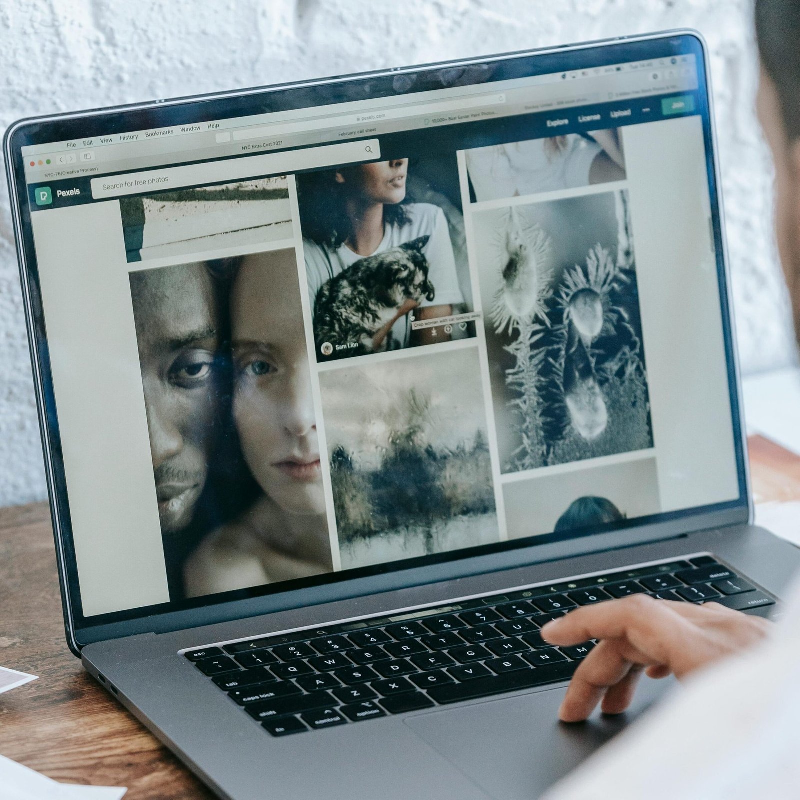 Back view of crop anonymous male freelancer sitting at table and working on project on laptop in light room in daytime